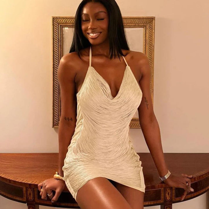 Woman in a beige dress sitting on a wooden table with a framed picture in the background