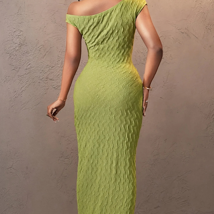 Green off-shoulder dress worn by a person against a beige wall