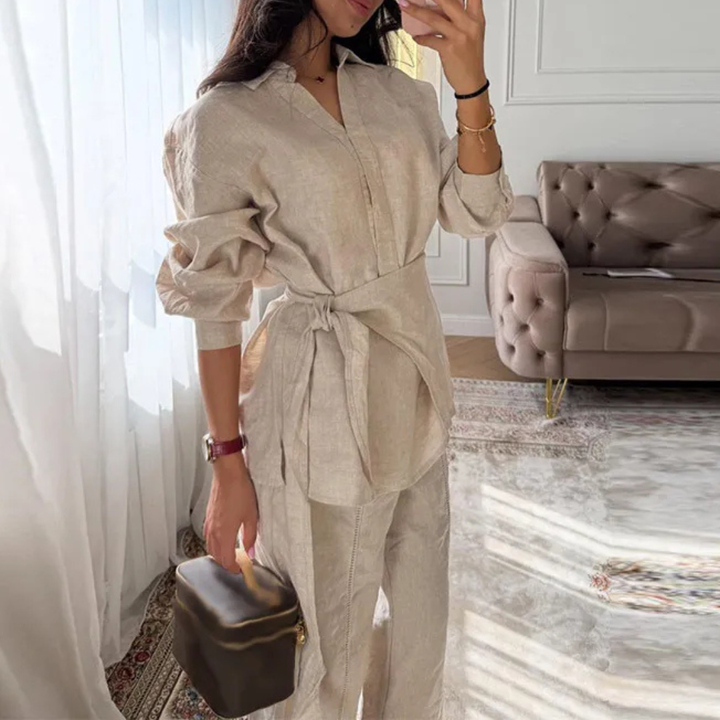 Woman in Apricot Alessia Elevated 2-Piece Set outfit holding a small bag in a room with a sofa and curtains.