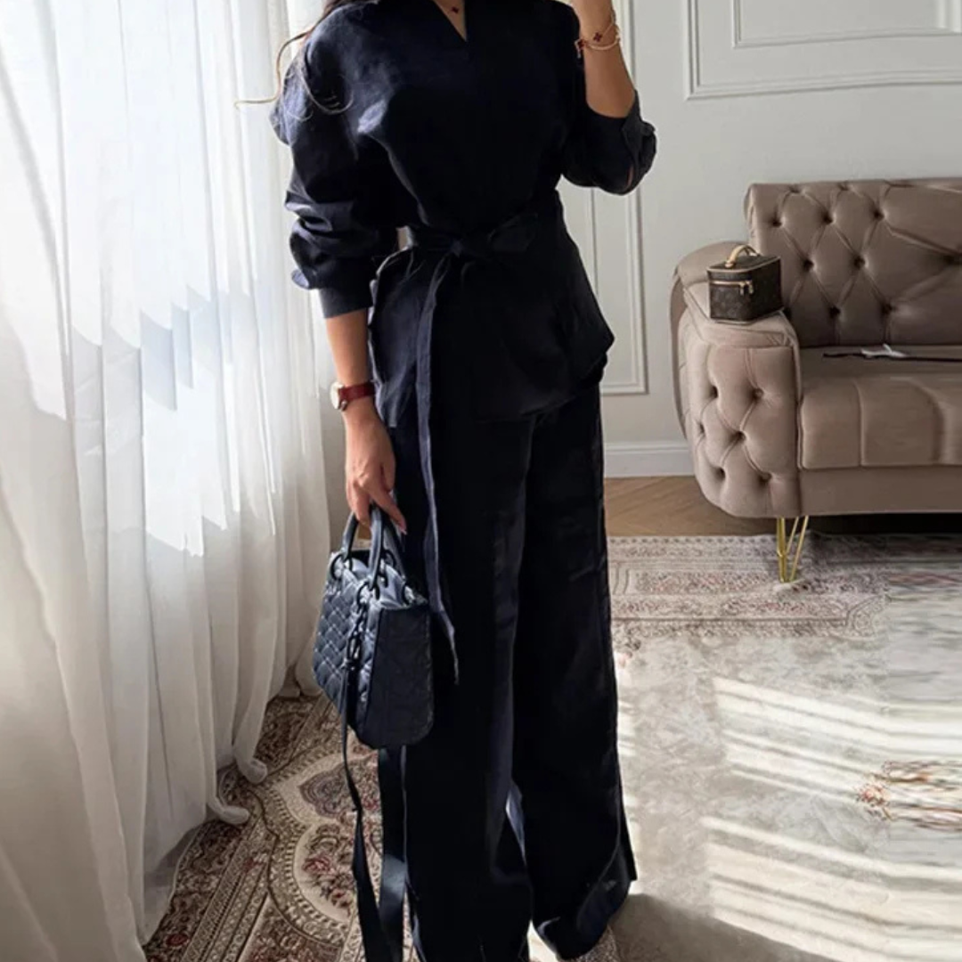 Person wearing a Navy Blue Alessia Elevated 2-Piece Set outfit holding a matching handbag in a stylish room.