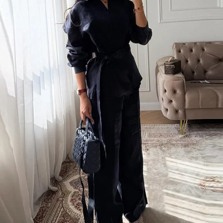 Person wearing a Navy Blue Alessia Elevated 2-Piece Set outfit holding a matching handbag in a stylish room.