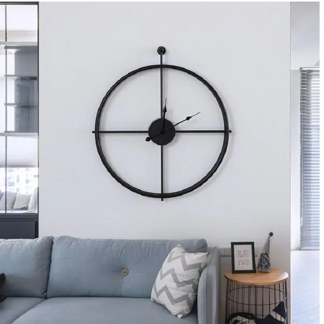Black Aurelle Modern Wall Clock on a white wall above a sofa in a living room.