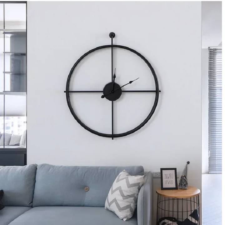 Black Aurelle Modern Wall Clock on a white wall above a sofa in a living room.