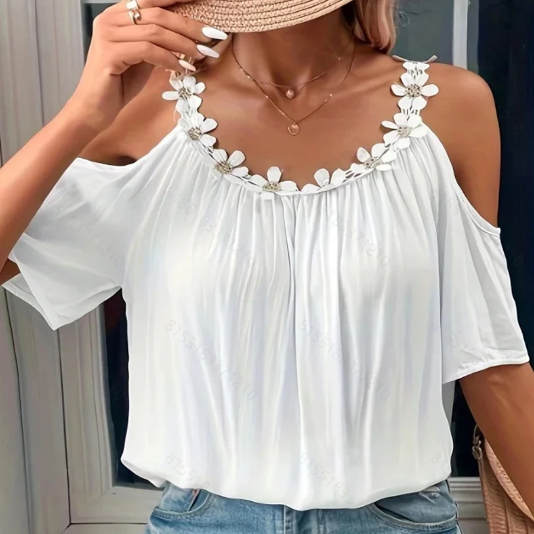 White off-shoulder top with floral details worn by a person.