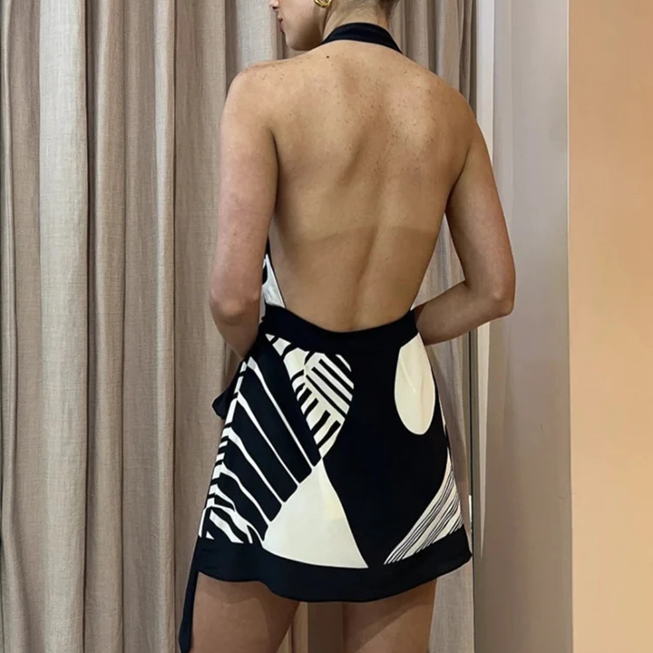 Person wearing a printed black patterned dress with a plain background