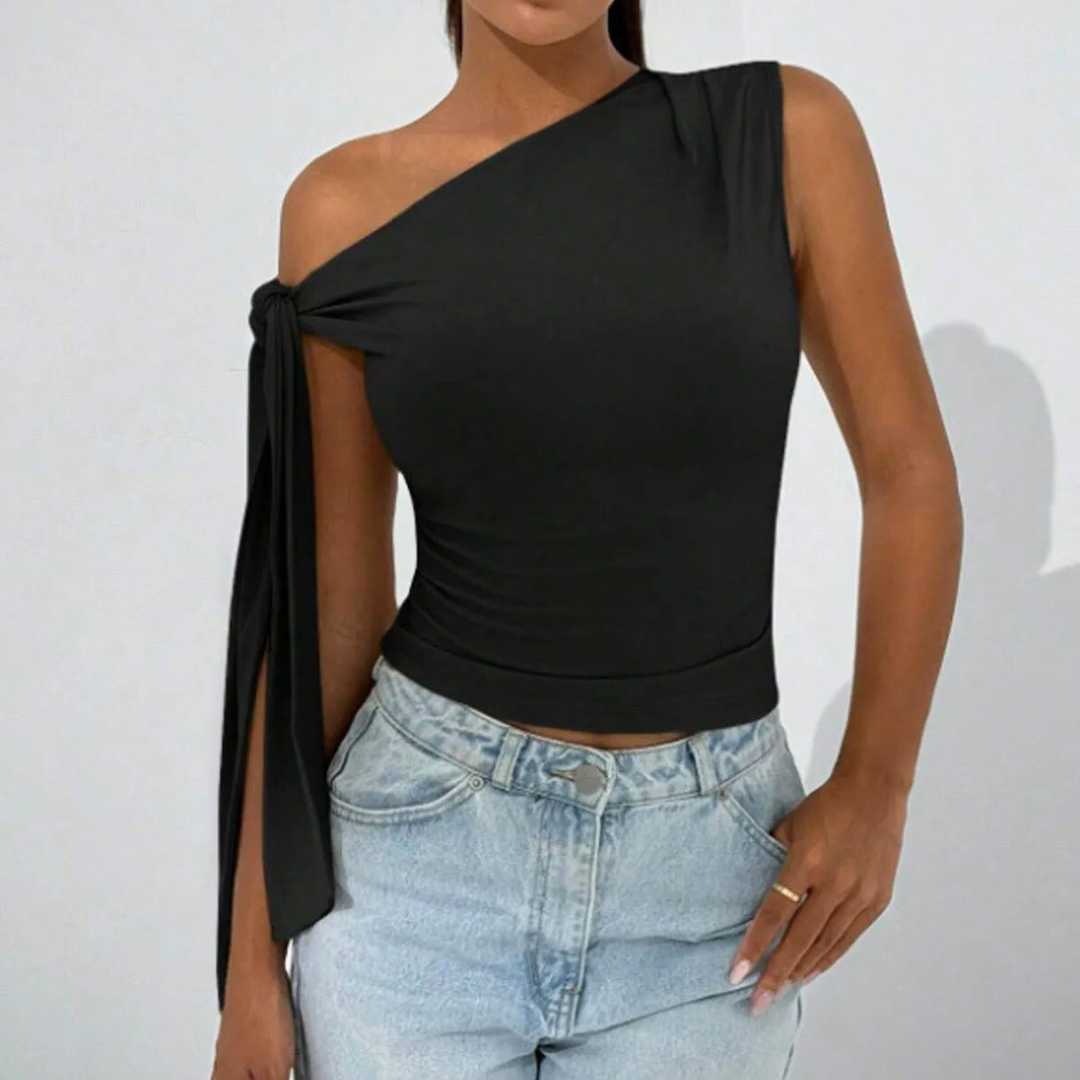 Person wearing a black one-shoulder top and blue jeans against a white background