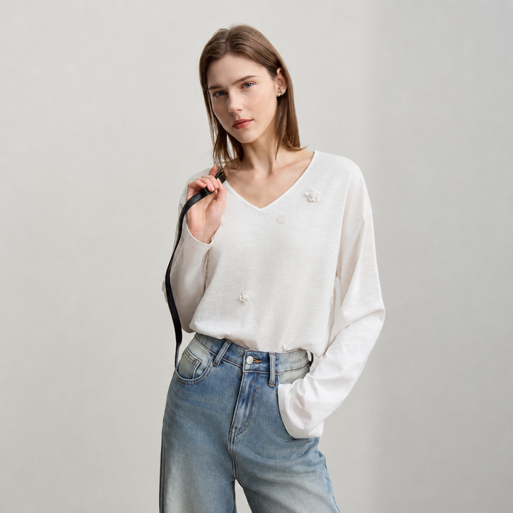 Woman wearing a beige blouse and blue jeans against a plain background