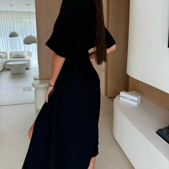 Woman wearing black Dahlia Statement Flow Midi Dress in indoor setting.