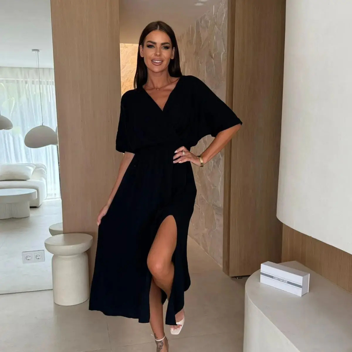 Woman wearing black Dahlia Statement Flow Midi Dress in indoor setting.