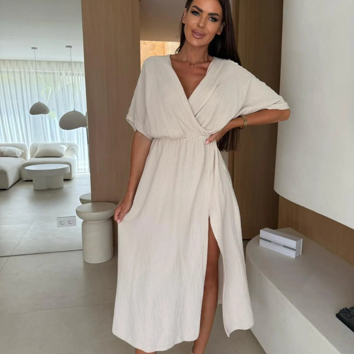 Woman in a white Dahlia Statement Flow Midi Dress standing in a modern interior setting