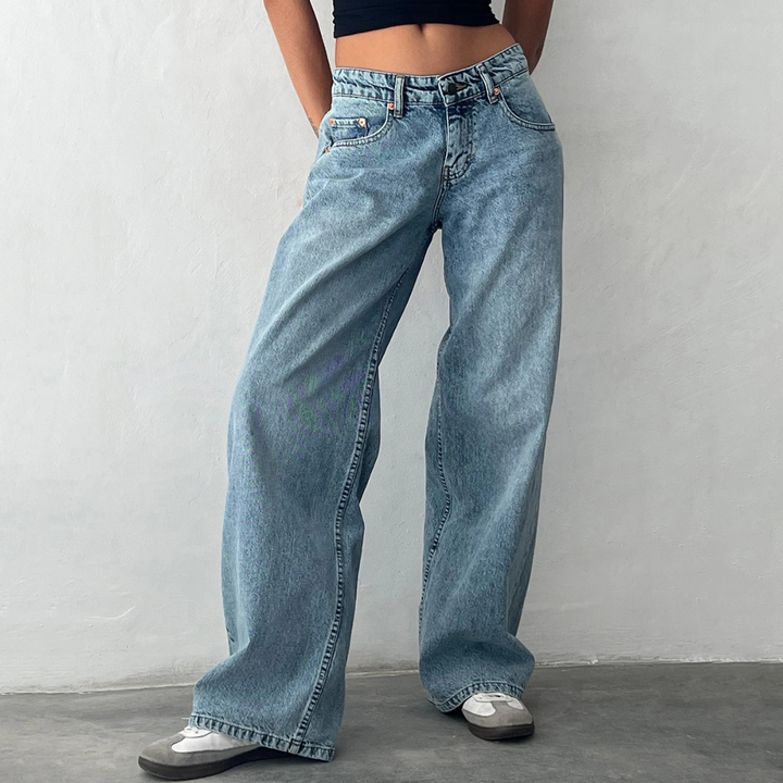 Person wearing light blue jeans against a plain background