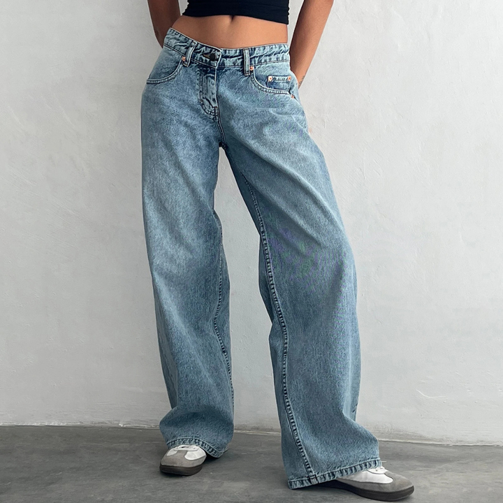 Person wearing light blue jeans against a plain background
