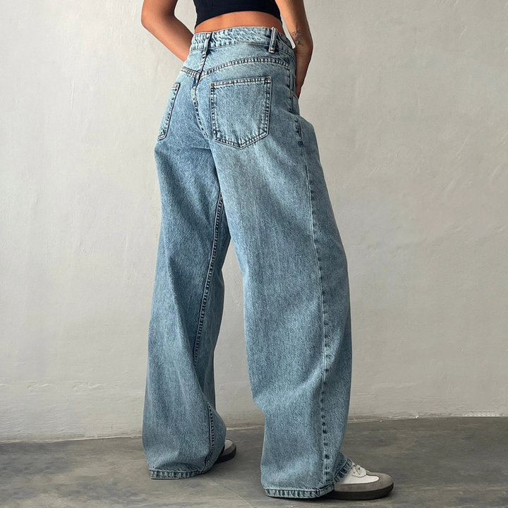 Person wearing light blue jeans against a plain background