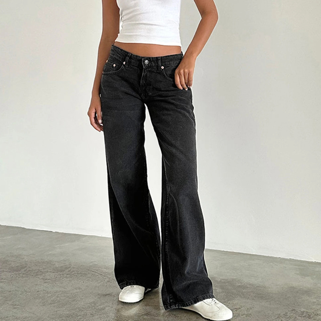 Person wearing black flared jeans and a white top on a plain background