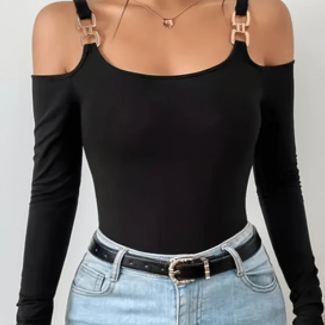 Black long-sleeve top worn with light blue jeans and a black belt on a plain background