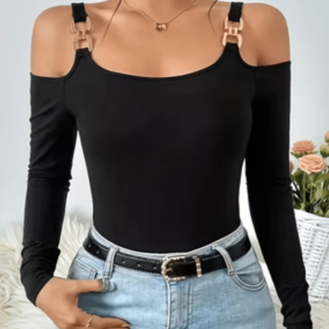 Person wearing a black long-sleeve top with cut-out shoulders and light blue jeans.