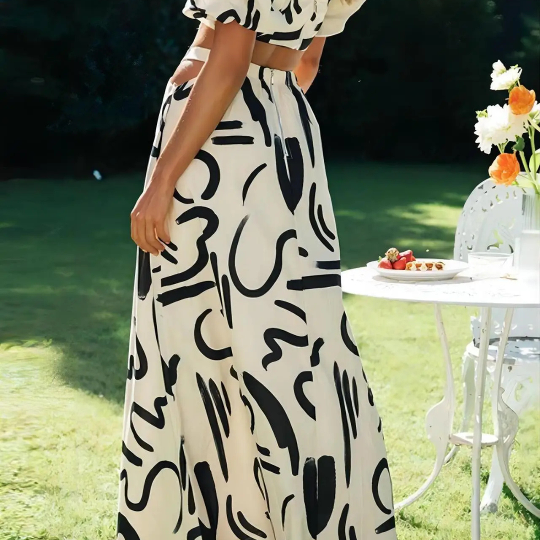 Person wearing a black and white abstract patterned dress in an outdoor setting.