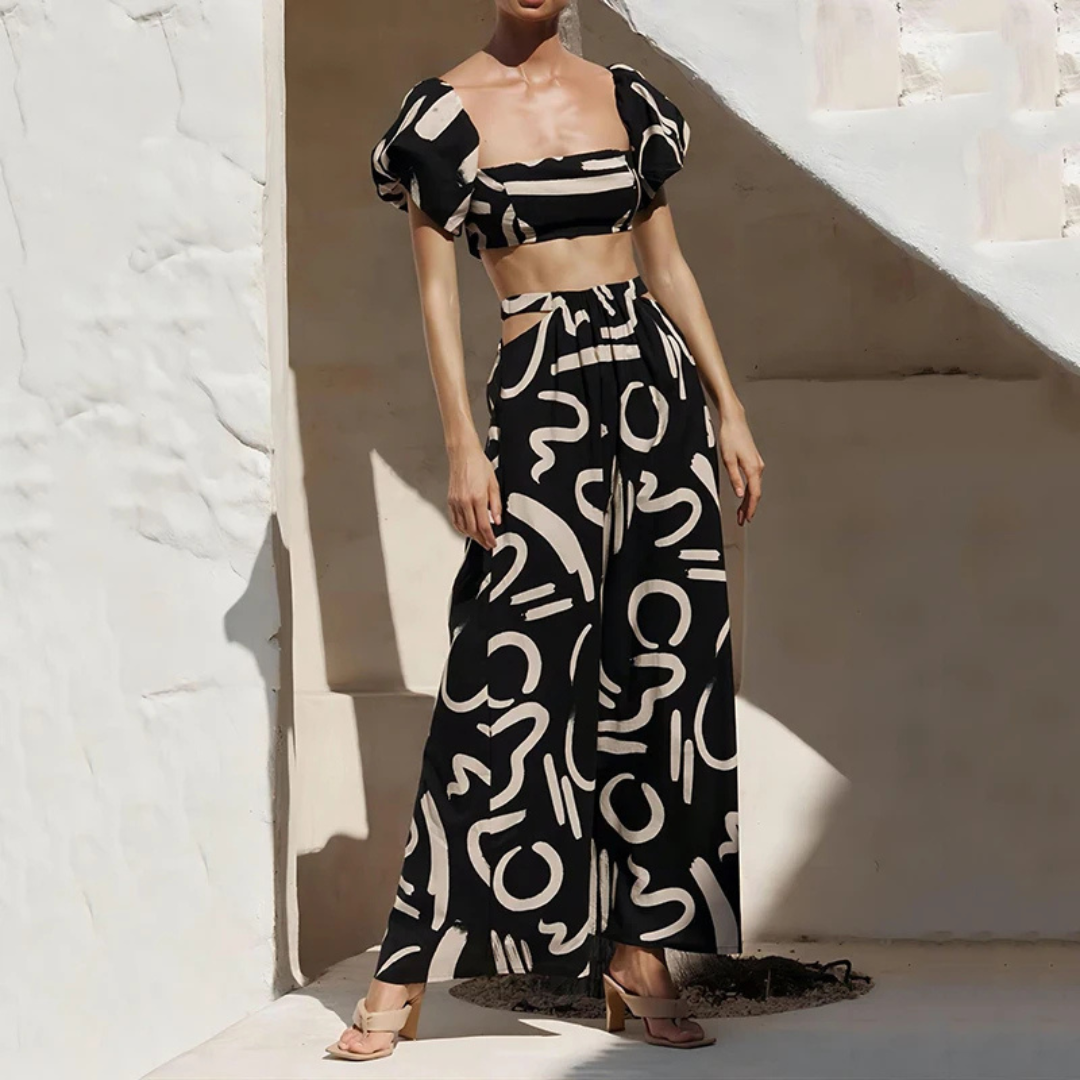 Woman wearing a black and white patterned outfit against a white wall.