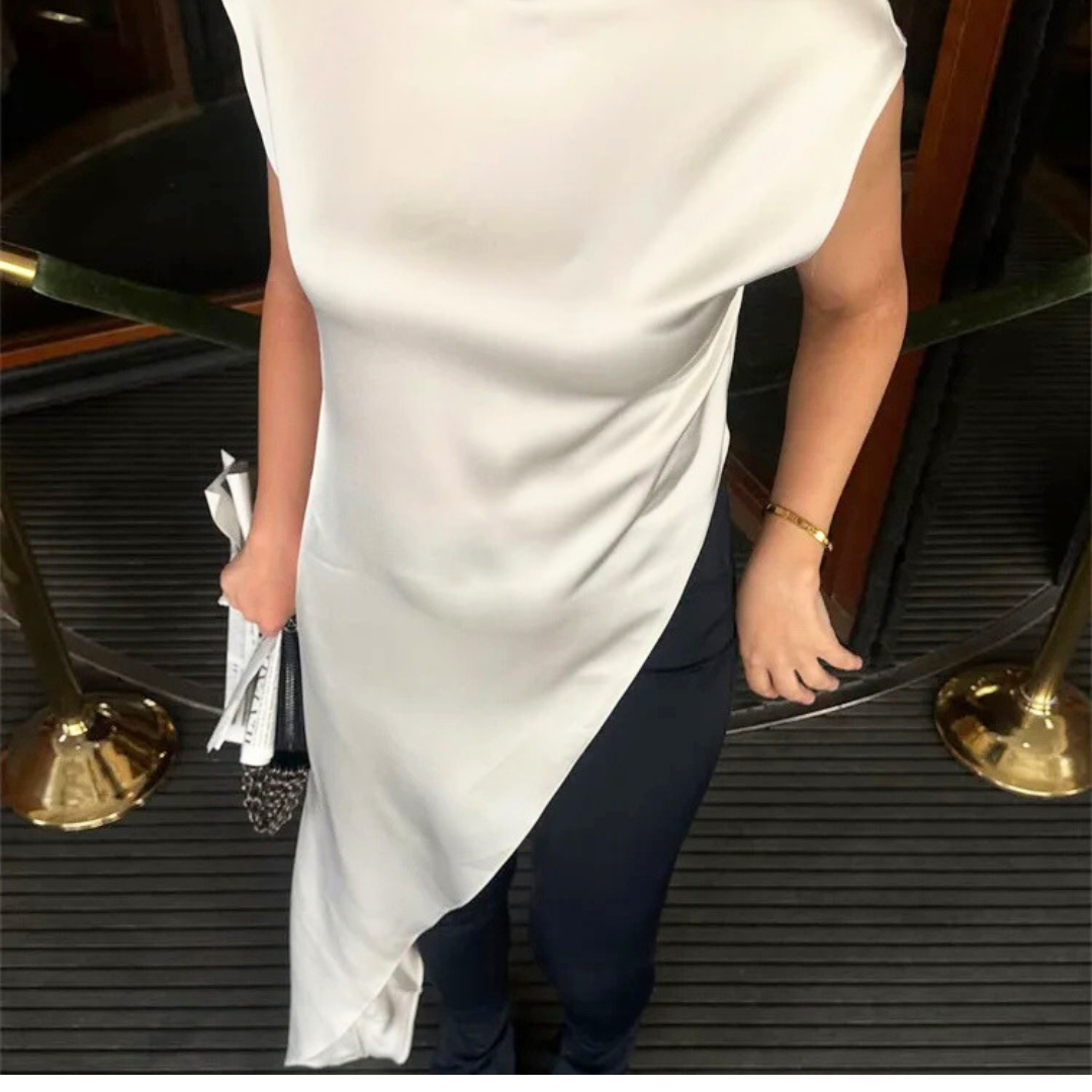 Person wearing a white dress and dark pants stepping onto a platform with gold accents.