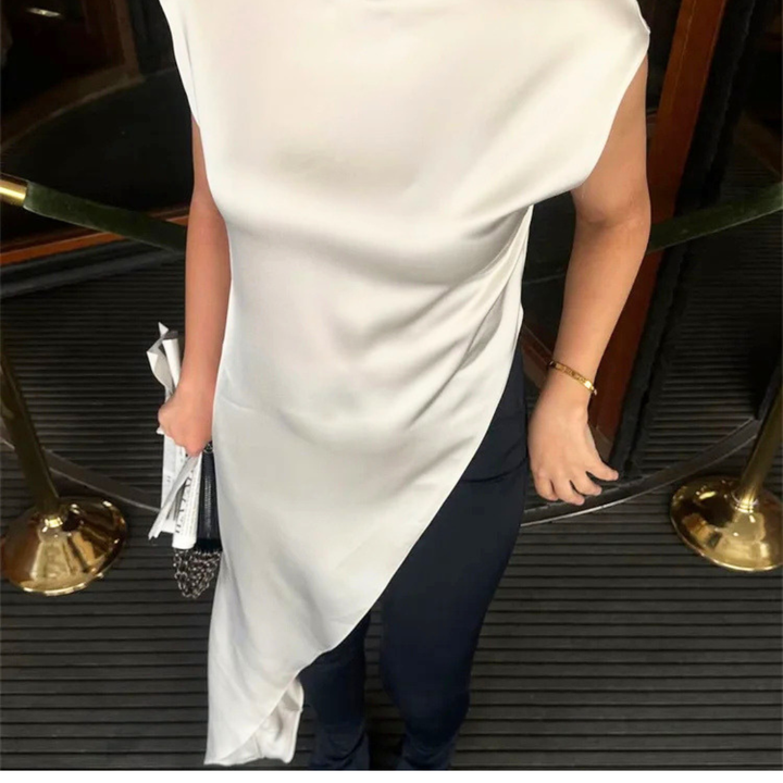 Person wearing a white dress and dark pants stepping onto a platform with gold accents.