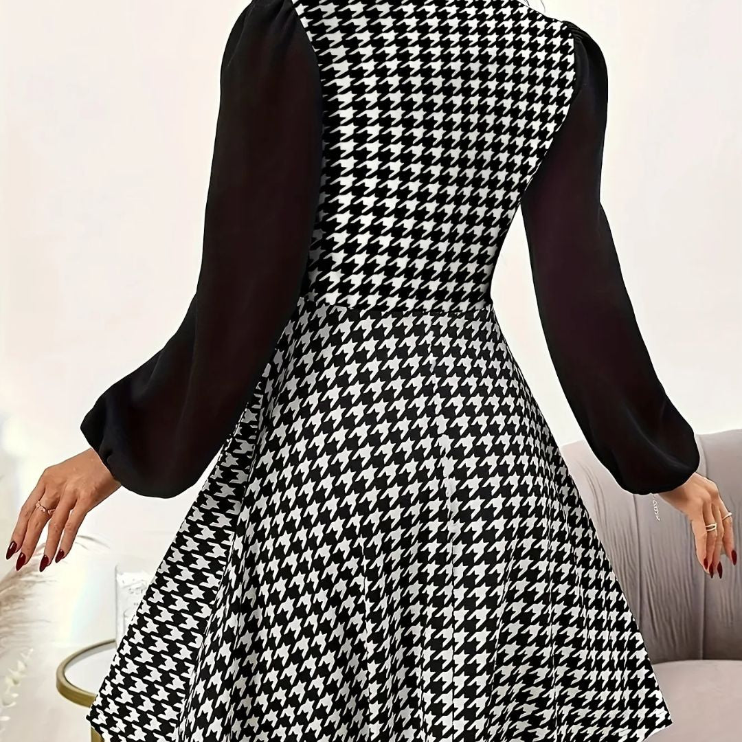 Black and white houndstooth patterned dress with long sleeves on a neutral background