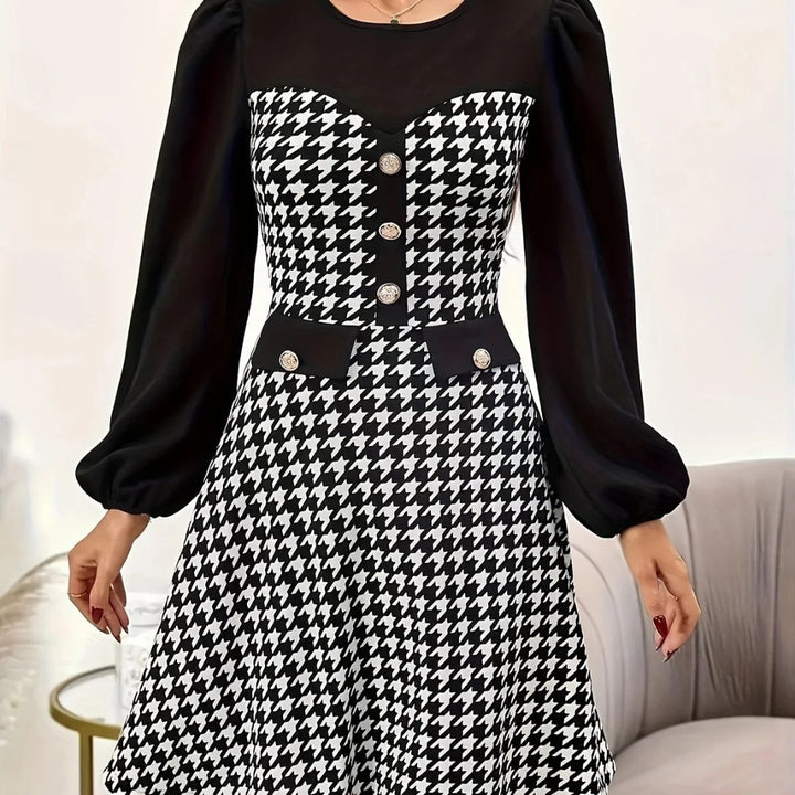 Black and white houndstooth pattern dress with long sleeves on a neutral background