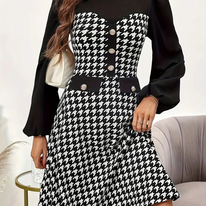 Person wearing a black and white houndstooth patterned dress with buttons.
