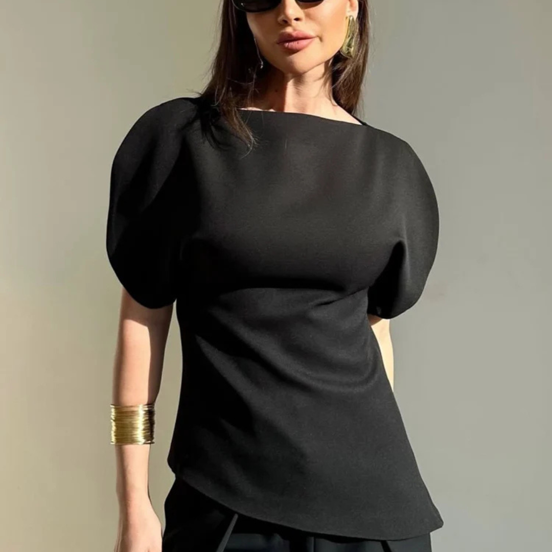 Woman wearing a black top with puffed sleeves against a neutral background