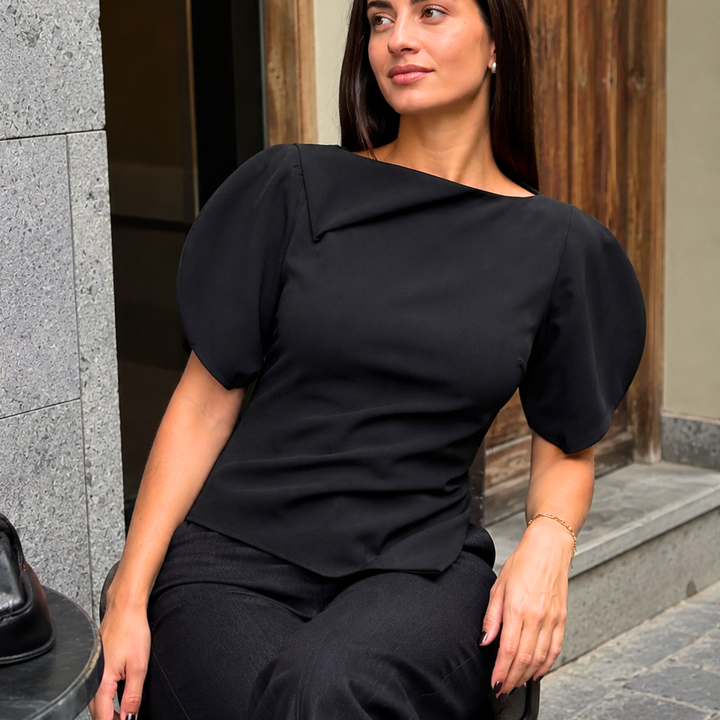 Woman wearing a black top sitting on a step outdoors.
