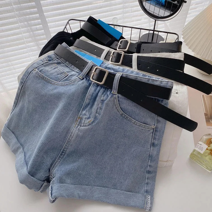 Folded Outlaw Muse Wide-Leg Denim Shorts with multiple belts on a white surface