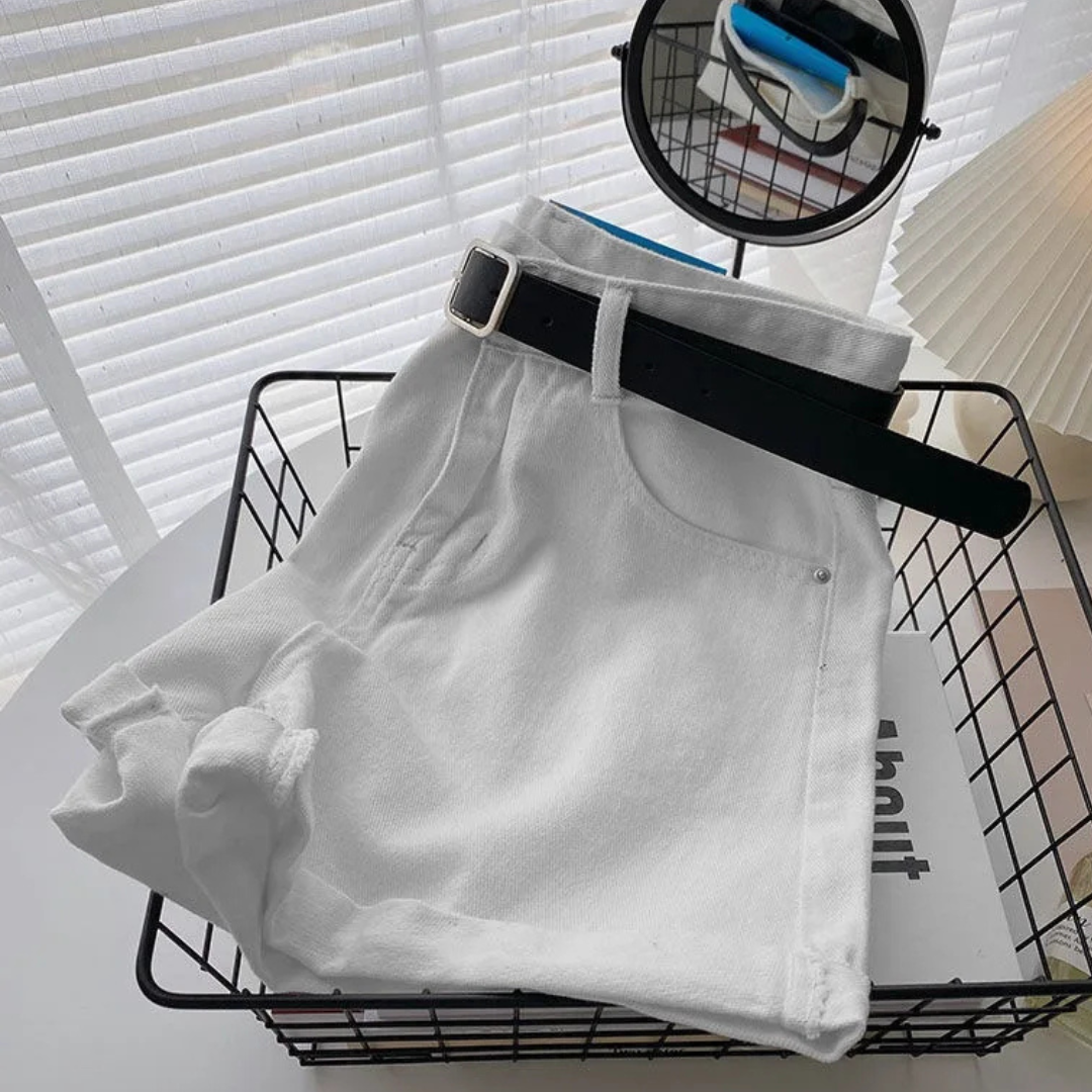 Outlaw Muse Wide-Leg White Denim Shorts with a black belt on a wire basket against a white background