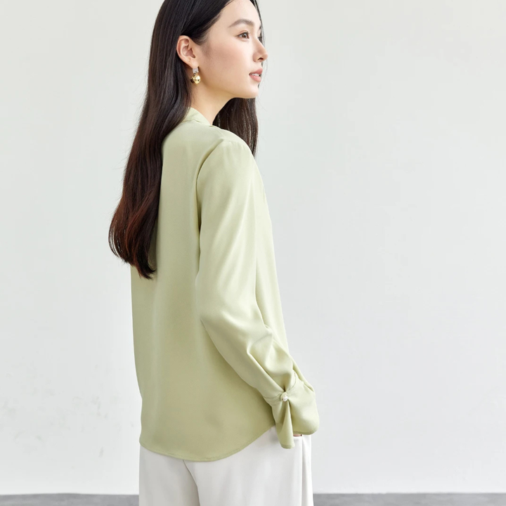 Woman wearing a light green blouse with a plain background