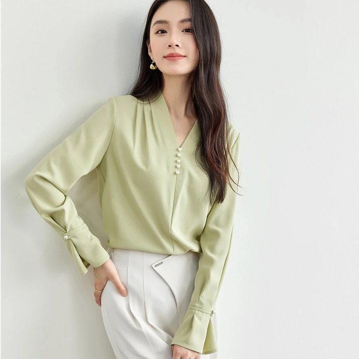 Woman wearing a light green blouse with a plain background
