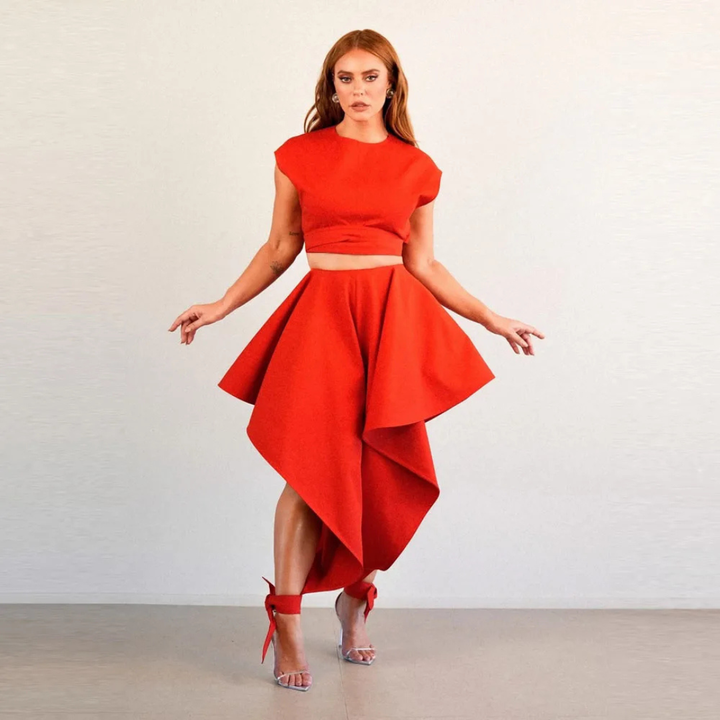 Woman wearing a red outfit with a flowing skirt on a plain background