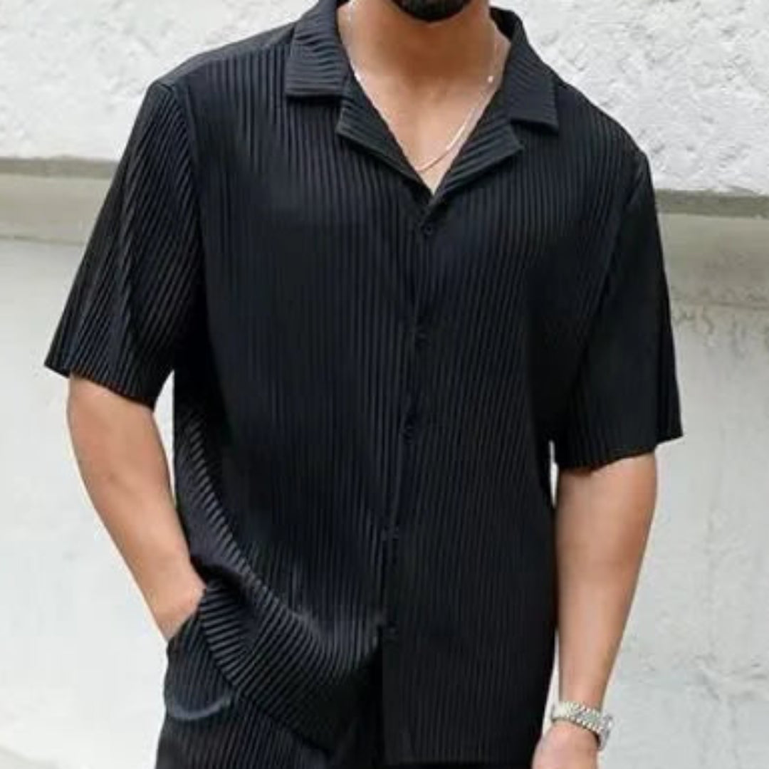 Man wearing a black striped shirt against a white wall.