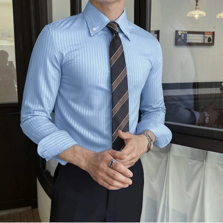 Person wearing a sky blue striped shirt and dark tie indoors.