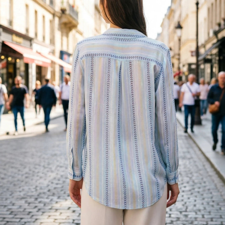 Woman wearing a blue striped shirt walking down a city street.