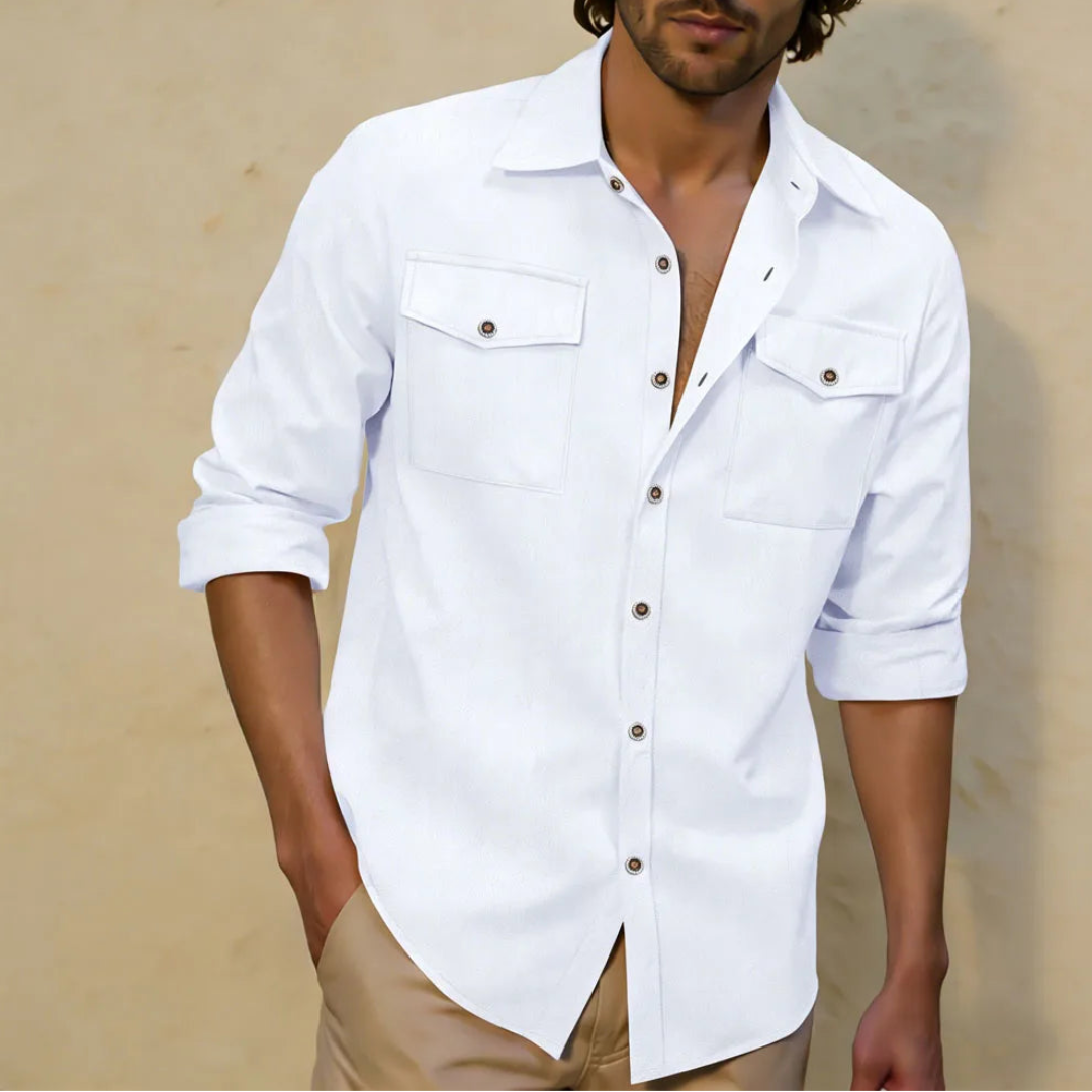 Man wearing a white button-up shirt with rolled-up sleeves against a beige background
