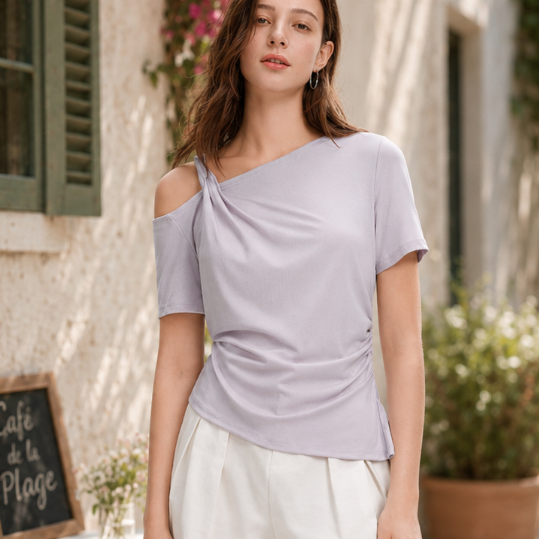 Woman wearing a light purple off-shoulder top and white pants outdoors.