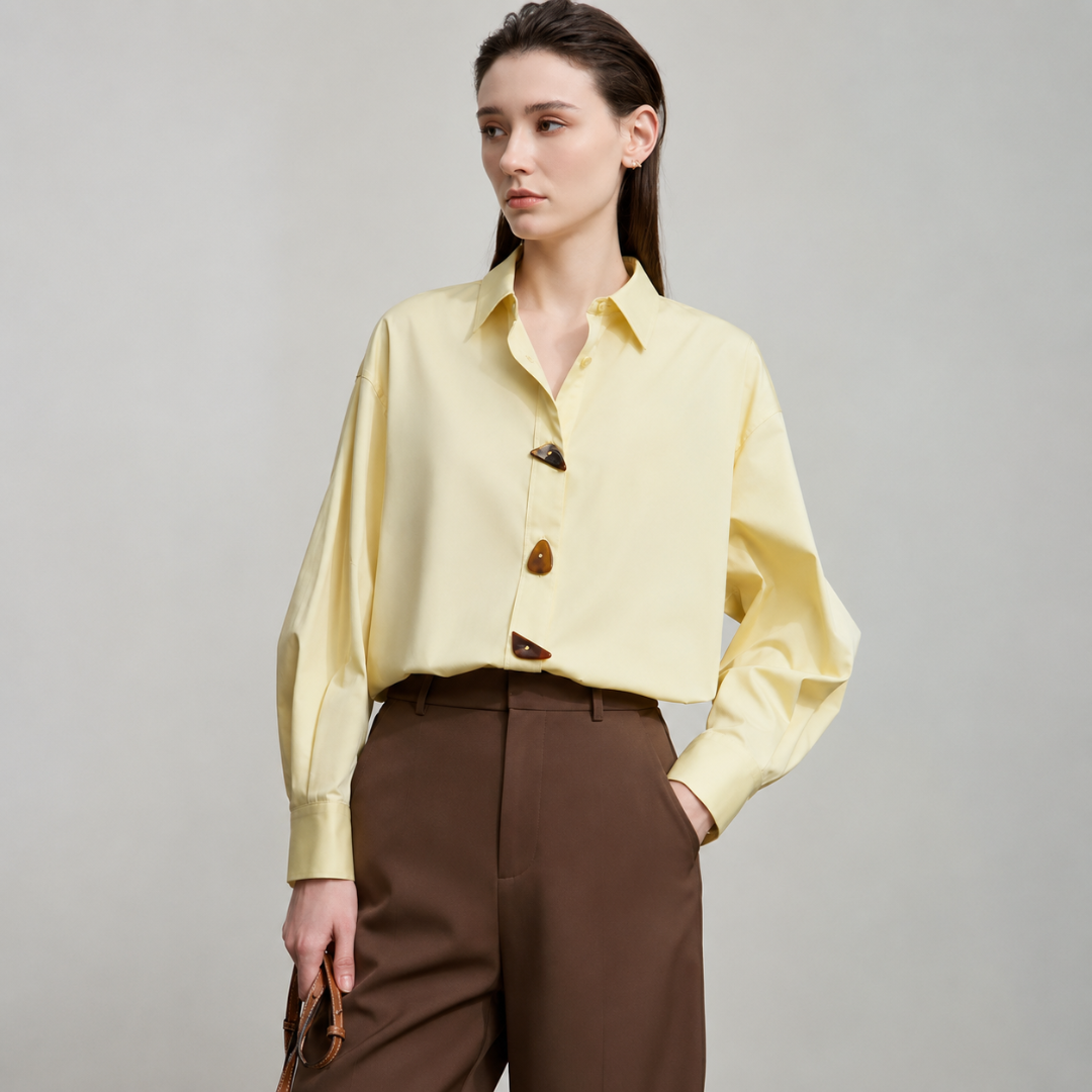 Woman wearing a yellow blouse and brown pants on a gray background