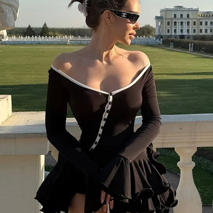 Woman in a black dress with white buttons standing on a balcony with a scenic background