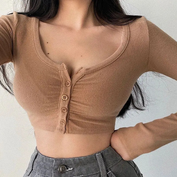 Person wearing a khaki ribbed crop top with button details against a light background