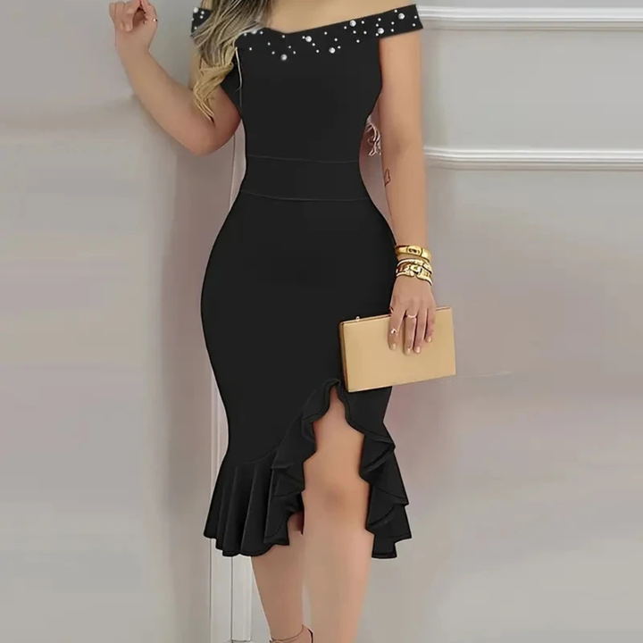 Black off-shoulder dress with ruffled hem and gold clutch against a neutral background
