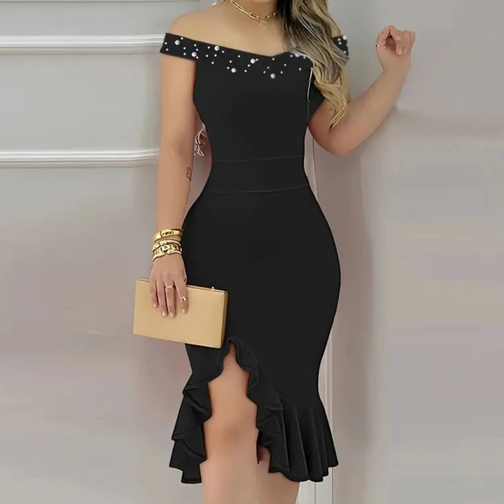Black off-shoulder dress with embellishments and a gold clutch against a neutral background