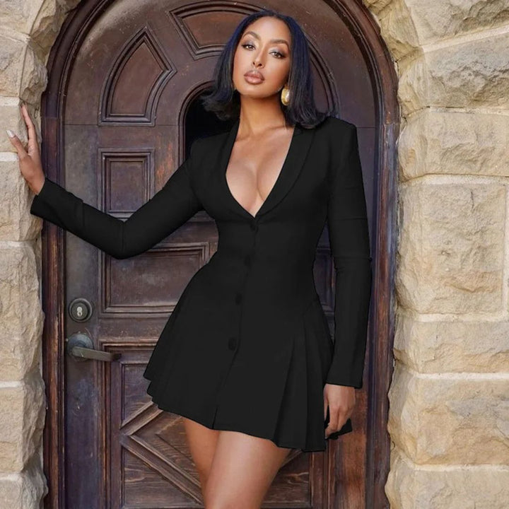 Woman in a black dress standing in front of a stone archway with a wooden door.