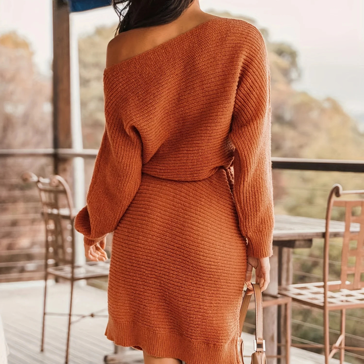 Person wearing a rust-colored knit dress on a balcony with blurred background