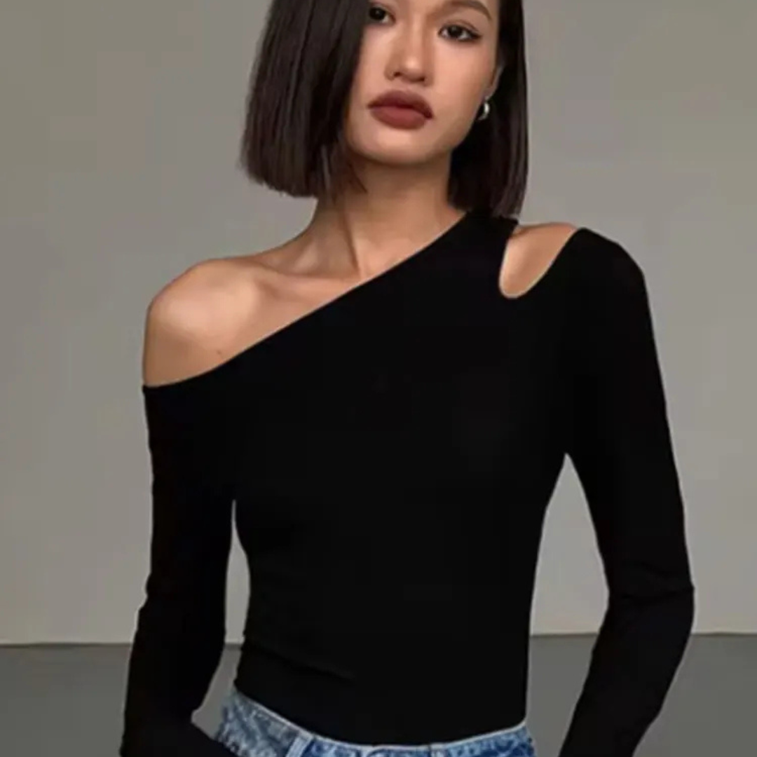 Woman wearing a black one-shoulder top against a plain background