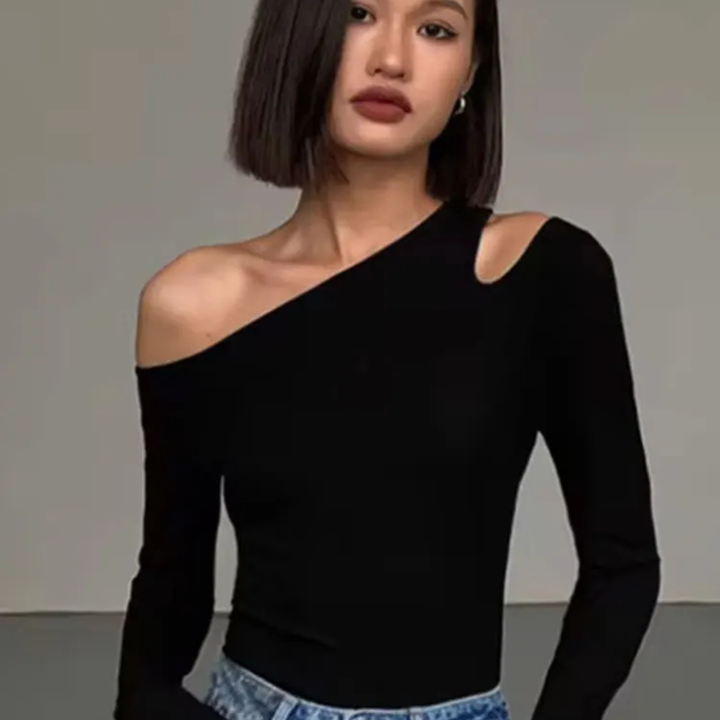 Woman wearing a black one-shoulder top against a plain background