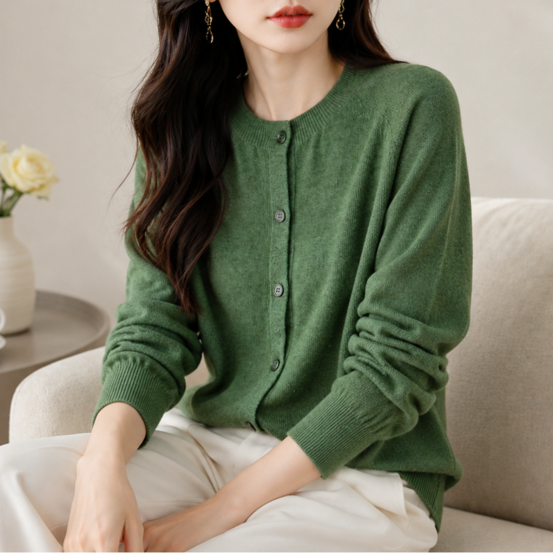 Woman wearing a green cardigan sitting on a couch in a cozy room.