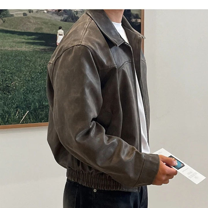 Person wearing a brown leather jacket indoors with a blurred outdoor scene in the background